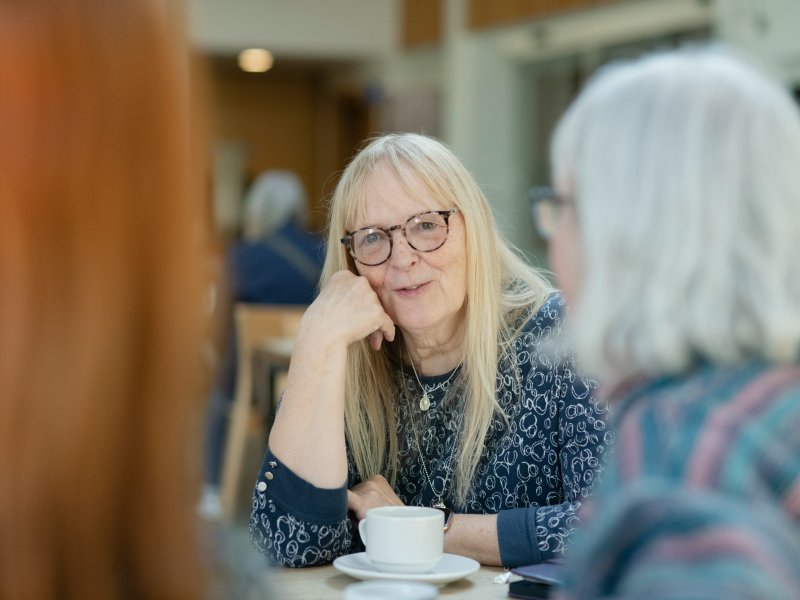 Female resident enjoying a hot drink with other residents