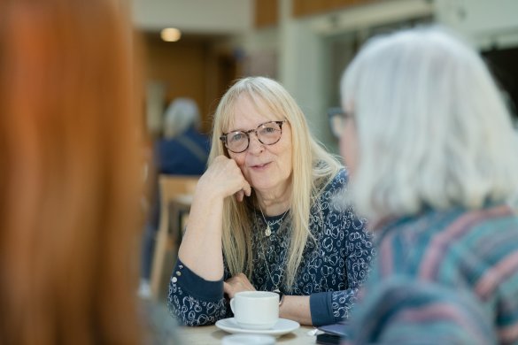 Female resident enjoying a hot drink with other residents