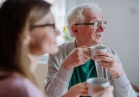 Male resident enjoying hot beverage and looking out of window