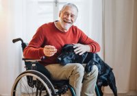 Wheelchair resident stroking black dog