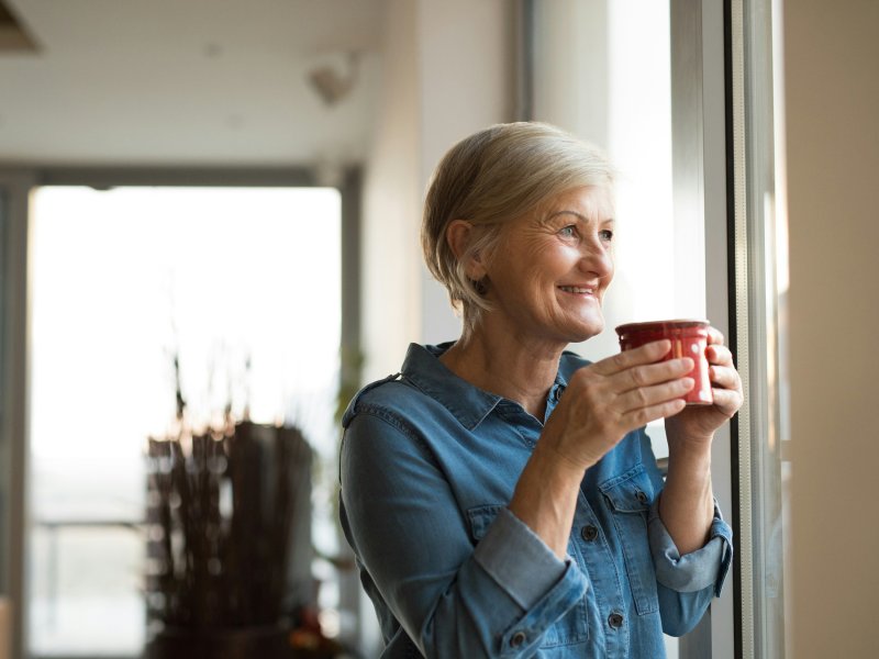 Woman looking out of the window drinking a cup of tea