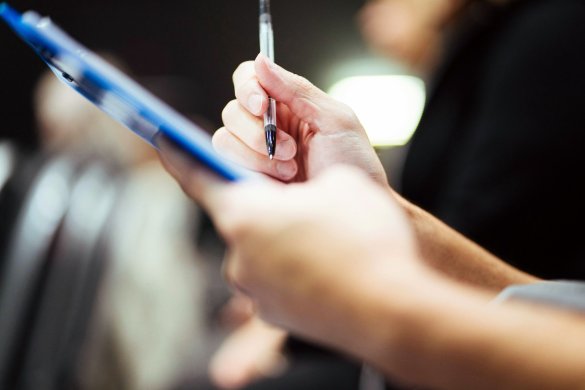 A person filling in a form on a clipboard