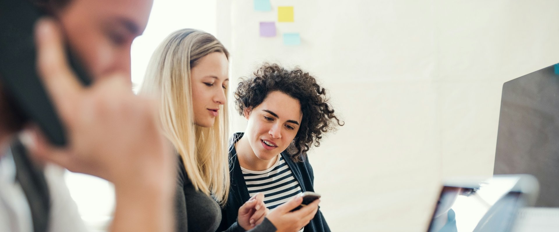 Two female workers looking at something on phone smiling.