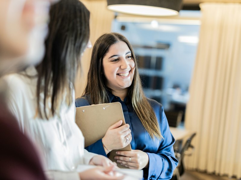 Female staff member holding clipboard and smiling