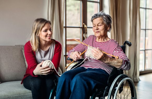 Female resident knitting with volunteer having a conversation